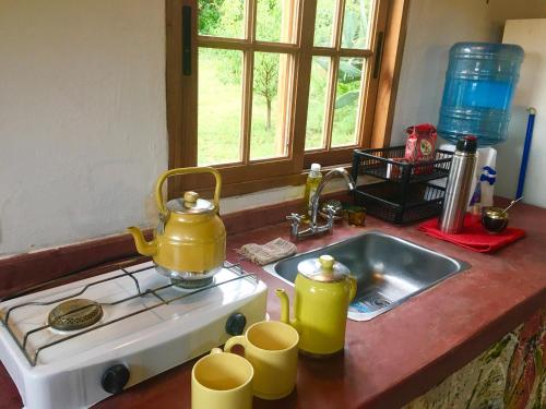 un fregadero de cocina con dos teteras amarillas. en Casa de montaña placentera en la naturaleza con vista espectacular en Traslasierra en Córdoba