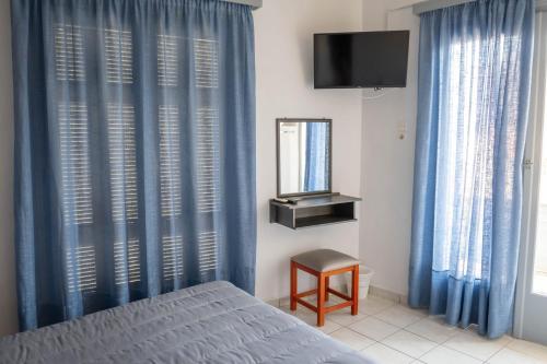 a bedroom with blue curtains and a bed and a mirror at Hotel Theoxenia in Argos