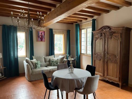 a living room with a table and a couch at Le prieuré des fontaines in Les Préaux