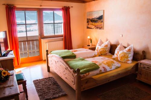 a bedroom with two beds and a large window at Almcafe Schnakenhöhe in Maria Rain