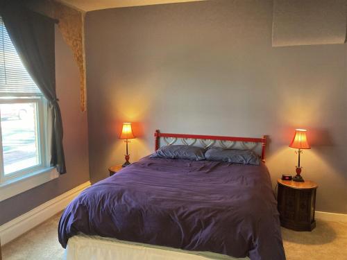 a bedroom with a bed with purple sheets and two lamps at La Casita Colorada, 12 Block To River Str#865 in Salida