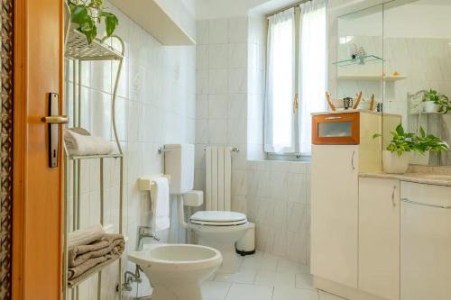 a white bathroom with a toilet and a sink at CASTLE&LAKE in Rezzonico