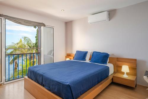 a bedroom with a blue bed and a balcony at Villa Beach Club in Santa Cruz