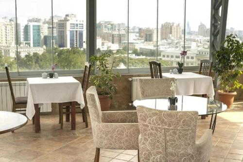 een restaurant met 2 tafels, stoelen en ramen bij Town Gates Hotel in Baku