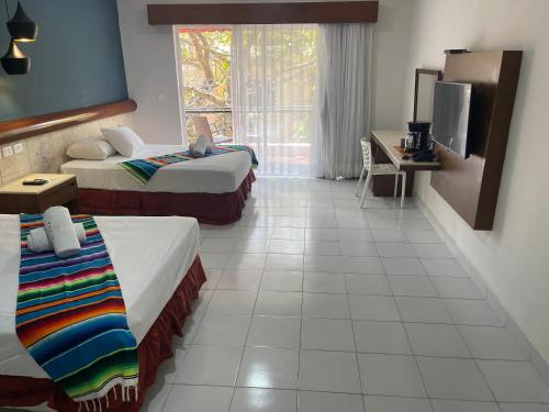a hotel room with two beds and a television at Hotel Mariachi by Kavia 5th Av in Playa del Carmen