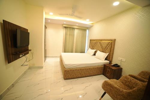 a bedroom with a bed and a tv and two chairs at OVEL HOTEL (SKY VIEW) in Ludhiana