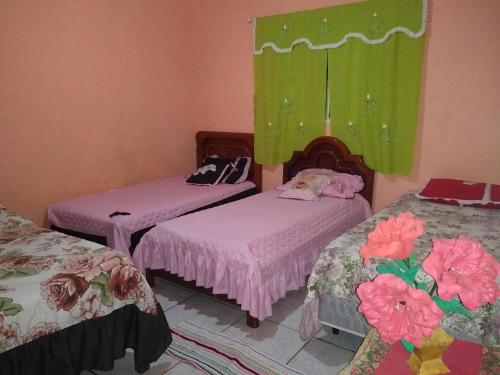 two beds in a room with pink and green curtains at Sítio Descanso E Natureza Igarapé - 20km Inhotim in Igarapé