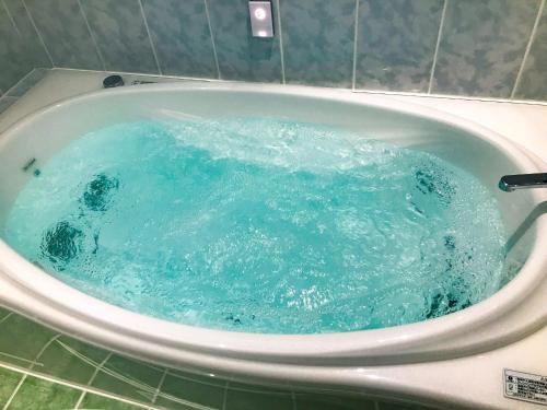 e bagno con vasca riempita di acqua blu. di Niruyakanaya BISE - Vacation STAY 68036v a Bise