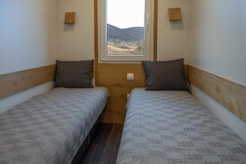 two beds in a small room with a window at Outdoor Resort Pecka in Mrkonjić Grad