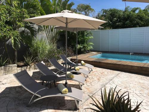 - un groupe de chaises et un parasol à côté de la piscine dans l'établissement Villa avec piscine privée, à Saint-François