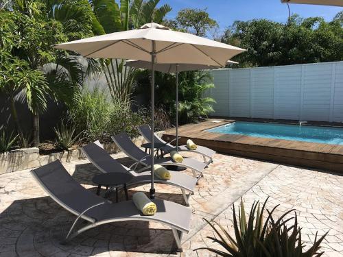 a group of chairs and an umbrella next to a pool at Villa avec piscine privée in Saint-François