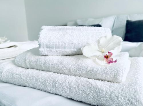 een stapel handdoeken met een bloem op een bed bij Luxe Apartments in Ljutomer