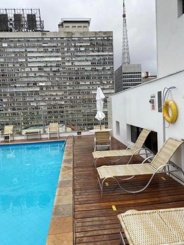 a balcony with a pool and chairs and a building at Flat Avenida Paulista - Trianon in São Paulo