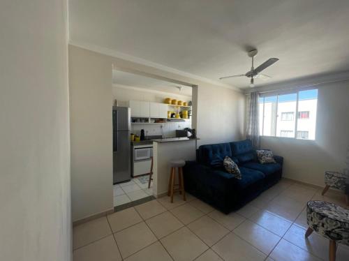 uma sala de estar com um sofá azul e uma cozinha em Apartamento - Dois Dormitórios - Todo Equipado em Bauru