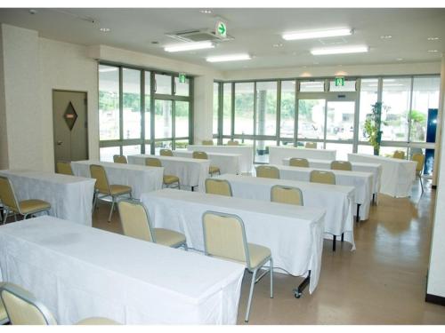 una stanza con tavoli e sedie bianchi e finestre di Hitoyoshi Onsen Hotel Hananoshou - Vacation STAY 40074v a Hitoyoshi