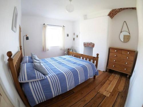 a bedroom with a bed and a wooden floor at Cosy Beachside Cottage in Bigbury