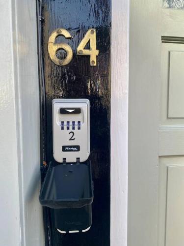 een huisnummer en een thermometer aan de zijkant van een deur bij 64 Bath Road - Central to Cheltenham in Cheltenham