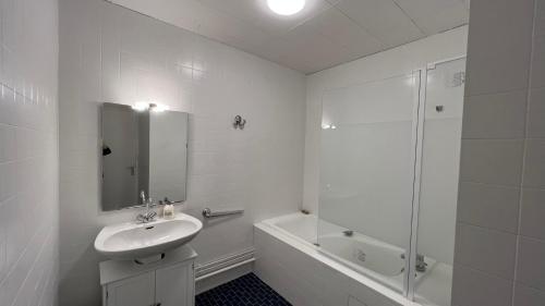 y baño blanco con lavabo y ducha. en Appartement T4 70m2 - meublé - centre ville - proche Thermes, en Lons-le-Saunier
