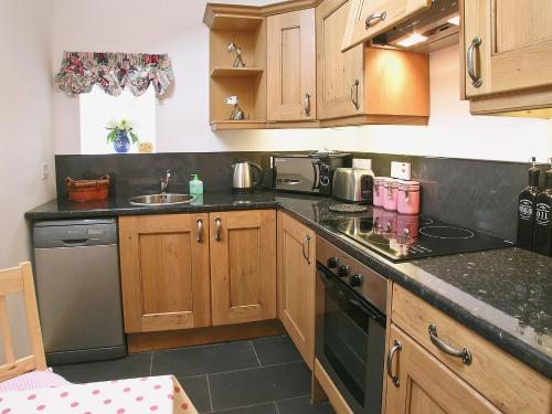 a kitchen with wooden cabinets and black counter tops at The Fauld in Gilsland