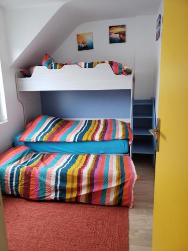 ein Schlafzimmer mit einem Etagenbett mit einer farbenfrohen Tagesdecke in der Unterkunft LE GALET BLANC in Fouesnant