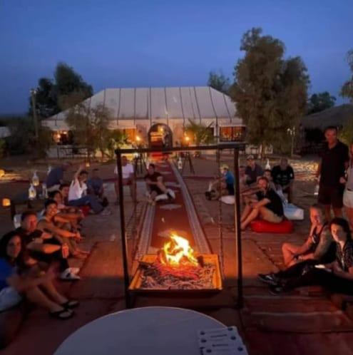 a group of people sitting around a fire pit at Merzouga Top Luxury Camp in Merzouga