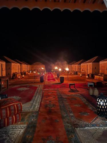 a night view of a courtyard with tables and buildings at Merzouga Top Luxury Camp in Merzouga