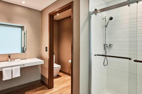 ein Bad mit einer Dusche, einem Waschbecken und einem WC in der Unterkunft AC Hotel by Marriott Cincinnati at The Banks in Cincinnati
