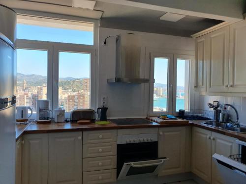 uma cozinha com armários brancos e vista para uma cidade em VISTAMALAGA em Málaga
