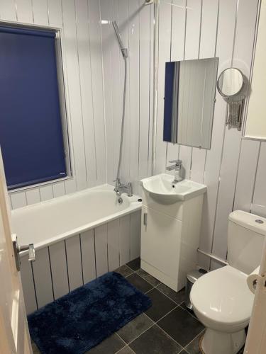 La salle de bains est pourvue de toilettes, d'une baignoire et d'un lavabo. dans l'établissement Spacious 3 bed flat near Watford Junction, à Watford
