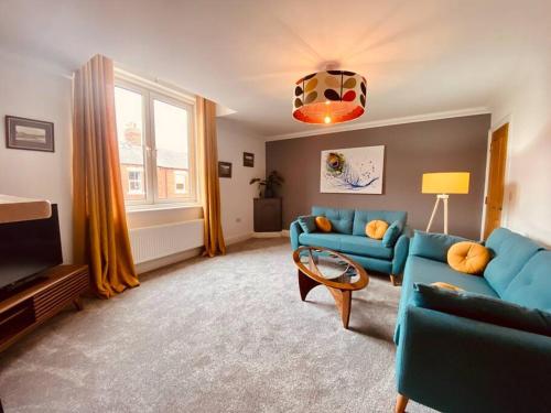 sala de estar con sofás azules y ventana en Luxury 2 bed apt 4 mins from M6 J44 pet friendly, en Carlisle