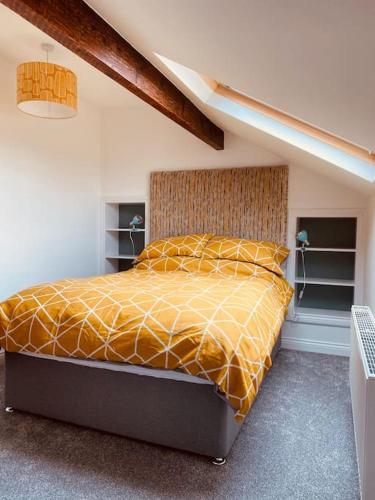 a bedroom with a bed with a yellow comforter at Luxury 2 bed apt 4 mins from M6 J44 pet friendly, in Carlisle