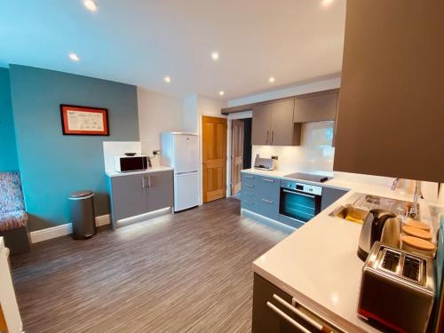 - une grande cuisine avec des appareils bleus et blancs dans l'établissement Luxury 2 bed apt 4 mins from M6 J44 pet friendly,, à Carlisle