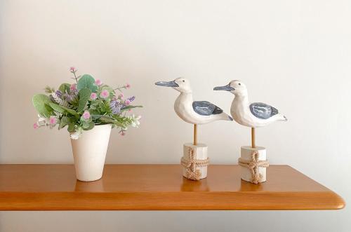 two birds sitting on a shelf next to a vase of flowers at Buzio e Mar in Portimão