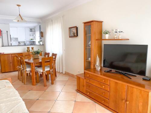 a living room with a television and a table with chairs at Buzio e Mar in Portimão