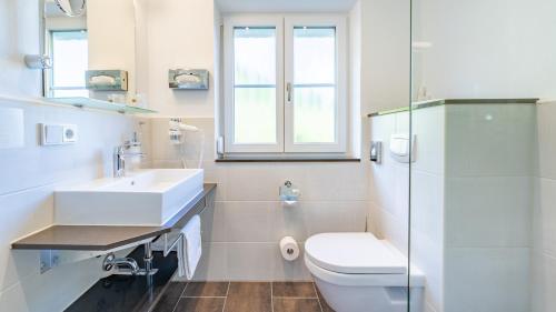 a white bathroom with a toilet and a sink at Hotel Steffl Garni inkl Chiemgau Karte in Ruhpolding