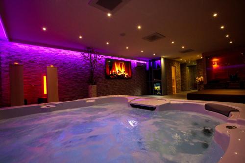 a large hot tub in a room with purple lighting at Privé Spa L'amour in Nuenen
