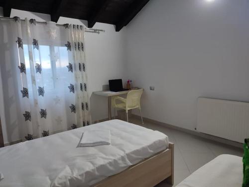 a bedroom with a bed and a desk with a laptop at Guest House Ilir in Berat