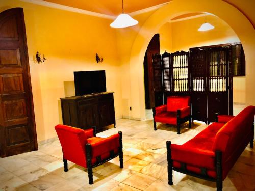 sala de estar con sillas rojas y TV en Dom Alberto Hostel en Corumbá