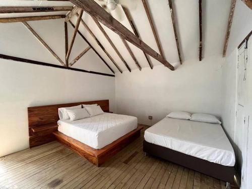 two beds in a room with white walls and wooden floors at finca playa seca in Santa Fe de Antioquia