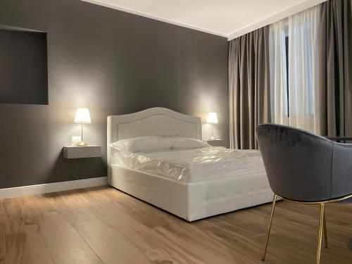a bedroom with a white bed and a chair at COMÓ EXCLUSIVE in Aprilia