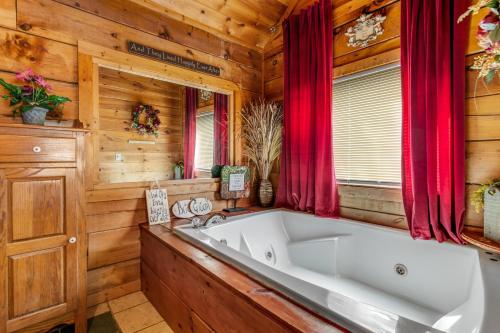 a large white tub in a wooden bathroom with red curtains at Snuggle Bear Hideaway in Pigeon Forge