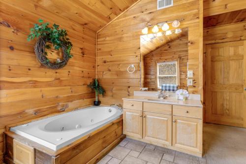 a bathroom with a tub and a sink in a log cabin at Papaw's Bear Den in Pigeon Forge