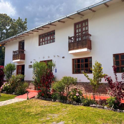 a white house with windows and a yard at Posada Del Valle Lodge in Urubamba
