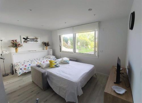 biała sypialnia z łóżkiem i oknem w obiekcie Appartement à Hendaye avec piscine et à côté de la plage w mieście Hendaye