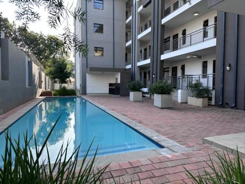 a swimming pool in front of a building at D&DLuxury Rivonia Apartments with inverter in Johannesburg