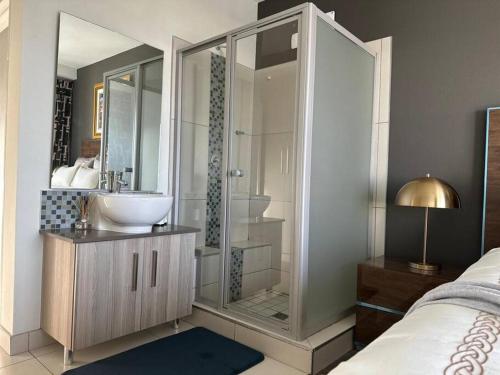 a bathroom with a sink and a glass shower at D&DLuxury Rivonia Apartments with inverter in Johannesburg