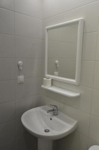 a white bathroom with a sink and a mirror at Pansion L'isola in Skiathos