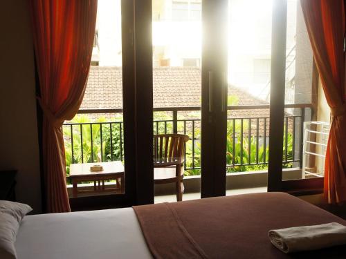 a bedroom with a bed and a view of a balcony at Waringin Homestay in Kuta