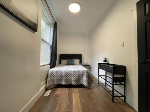 a bedroom with a bed and a desk and a window at Charming Century Apartments, Steps to downtown in London