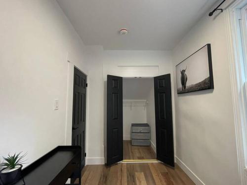 a hallway with two black doors and a dresser at Charming Century Apartments, Steps to downtown in London